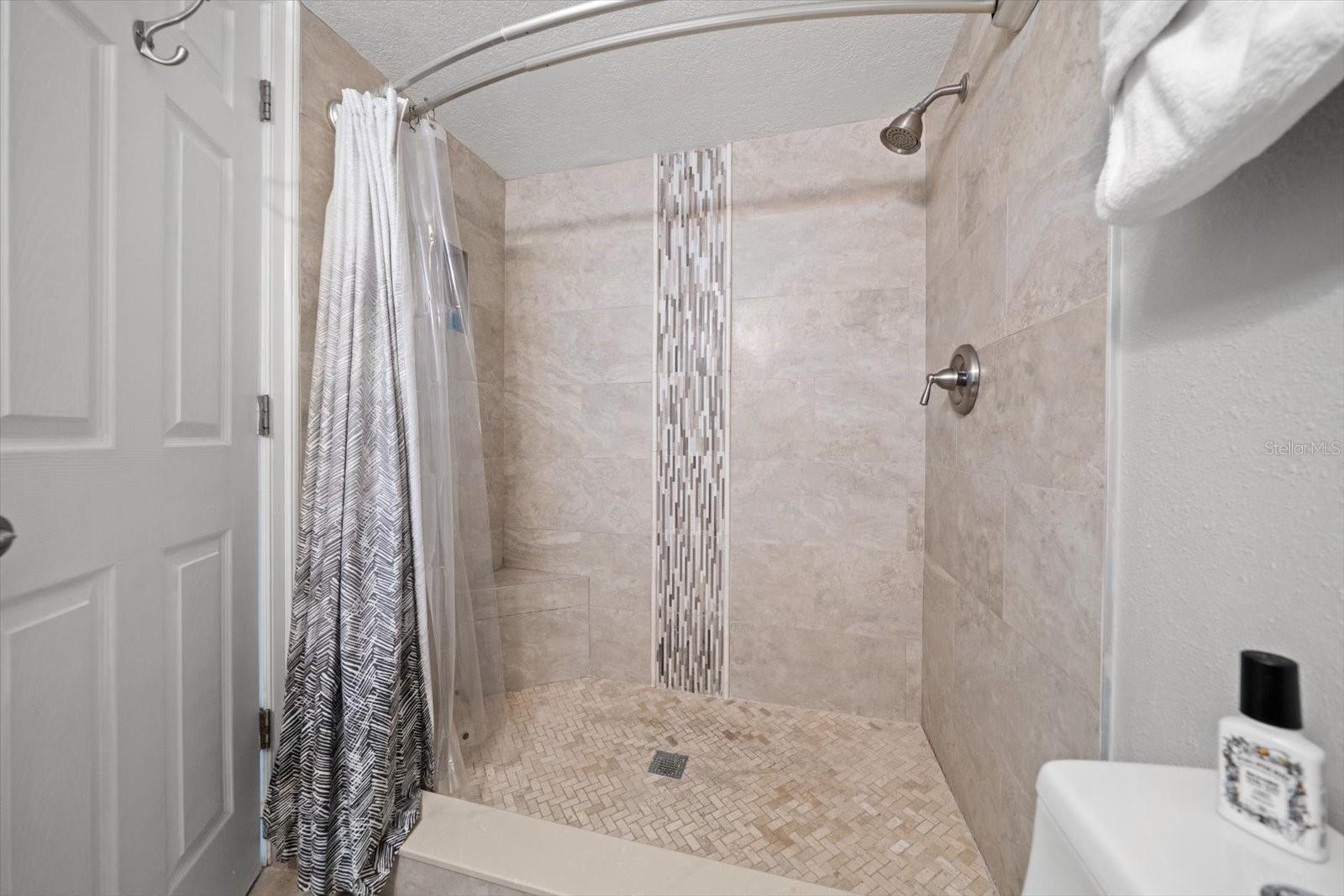 Spacious walk in shower with attractive vertical tile inlay.