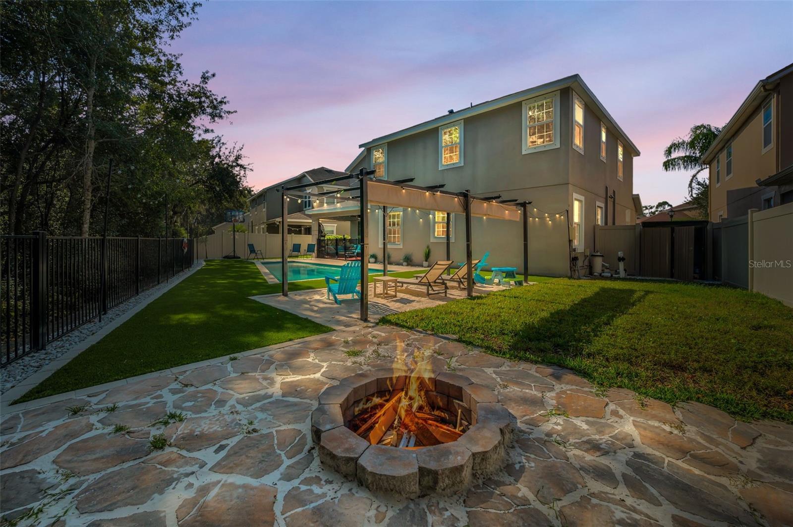 rear of home, fire pit, beach area pergola, lanai, shed, and pool pump-twilight