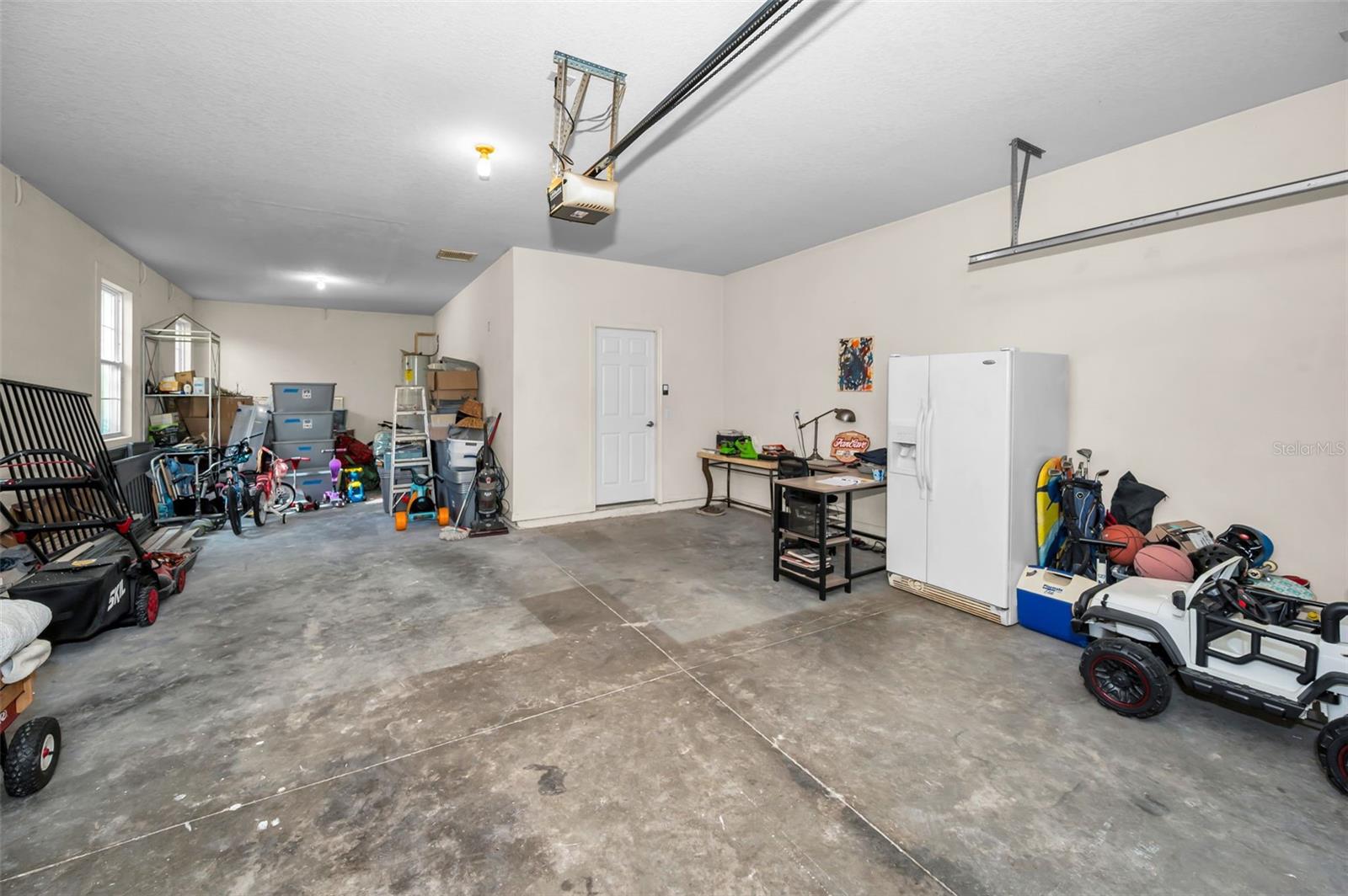 3 car garage w/ hurricane strength garage door looking toward the laundry room entrance (garage fridge doesn't convey)