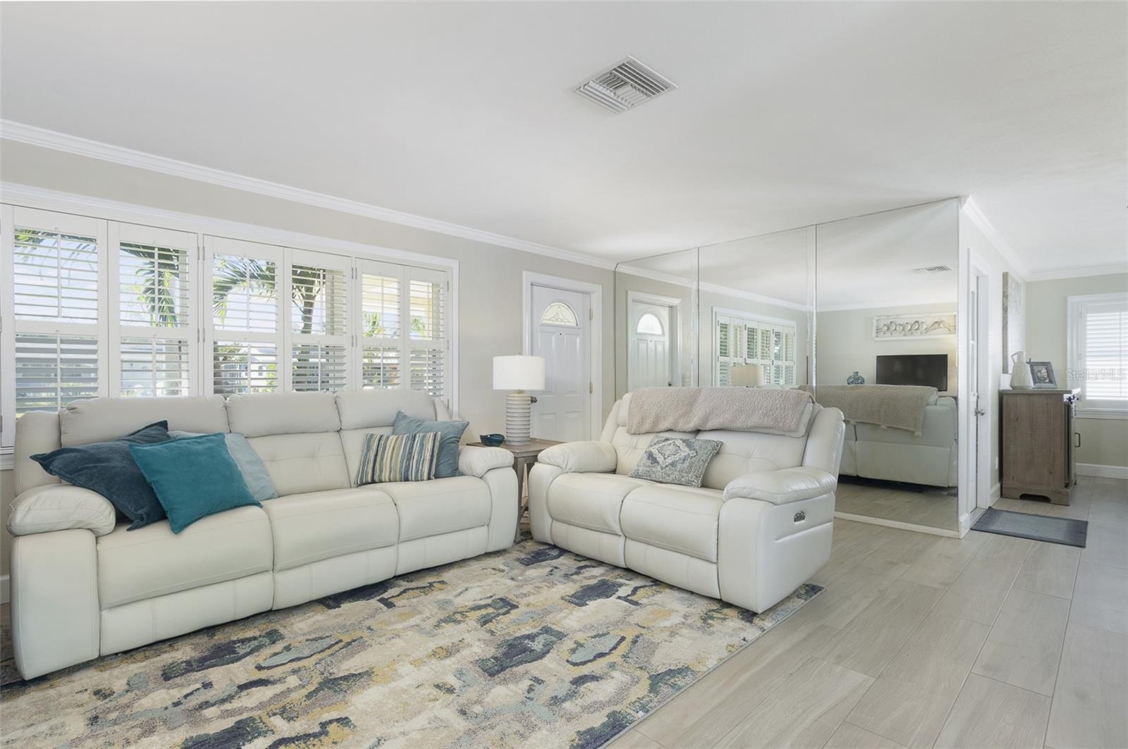 Notice the beautiful details of the ceramic tile floors that look like wood, crown molding, a mirrored wall for this last minutes checks before loeaving the home, and the plantation shutters.