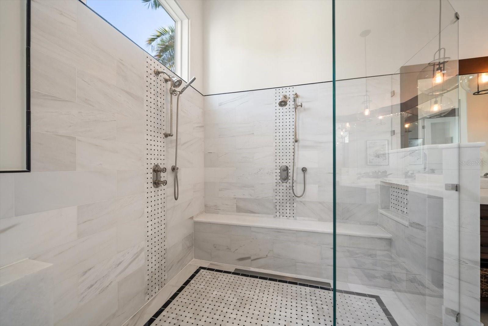 Zero entry walk in shower with bench seat and two shower heads and adjustable handheld heads