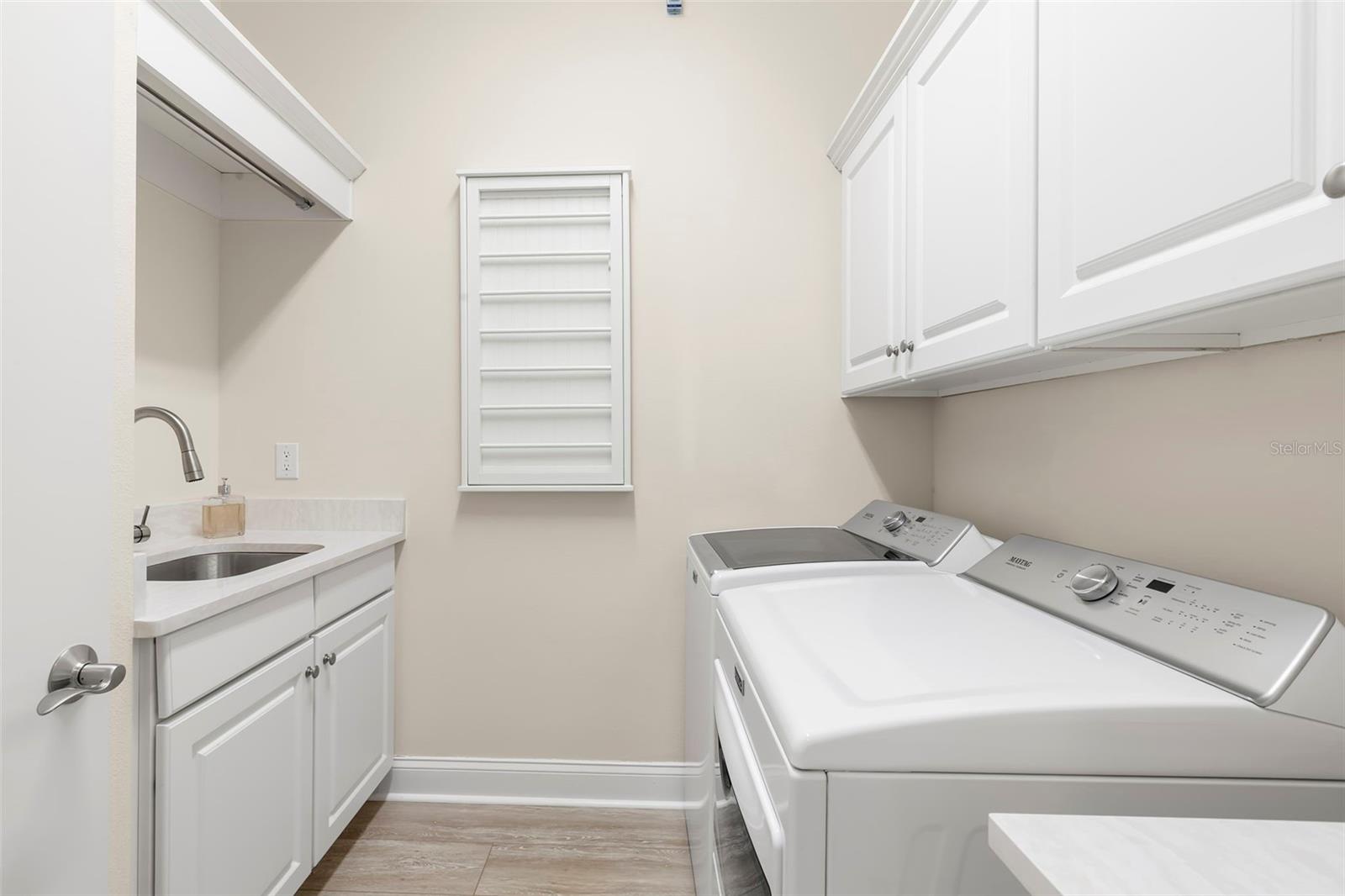 Oversized laundry room features extra storage, laundry sink, hanging space and counter space.