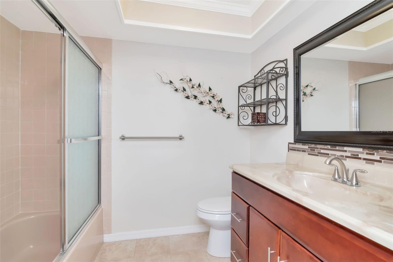 Updated hall bathroom also has tray ceiling with new vanity & commode fixtures, glass doors on tub/shower~