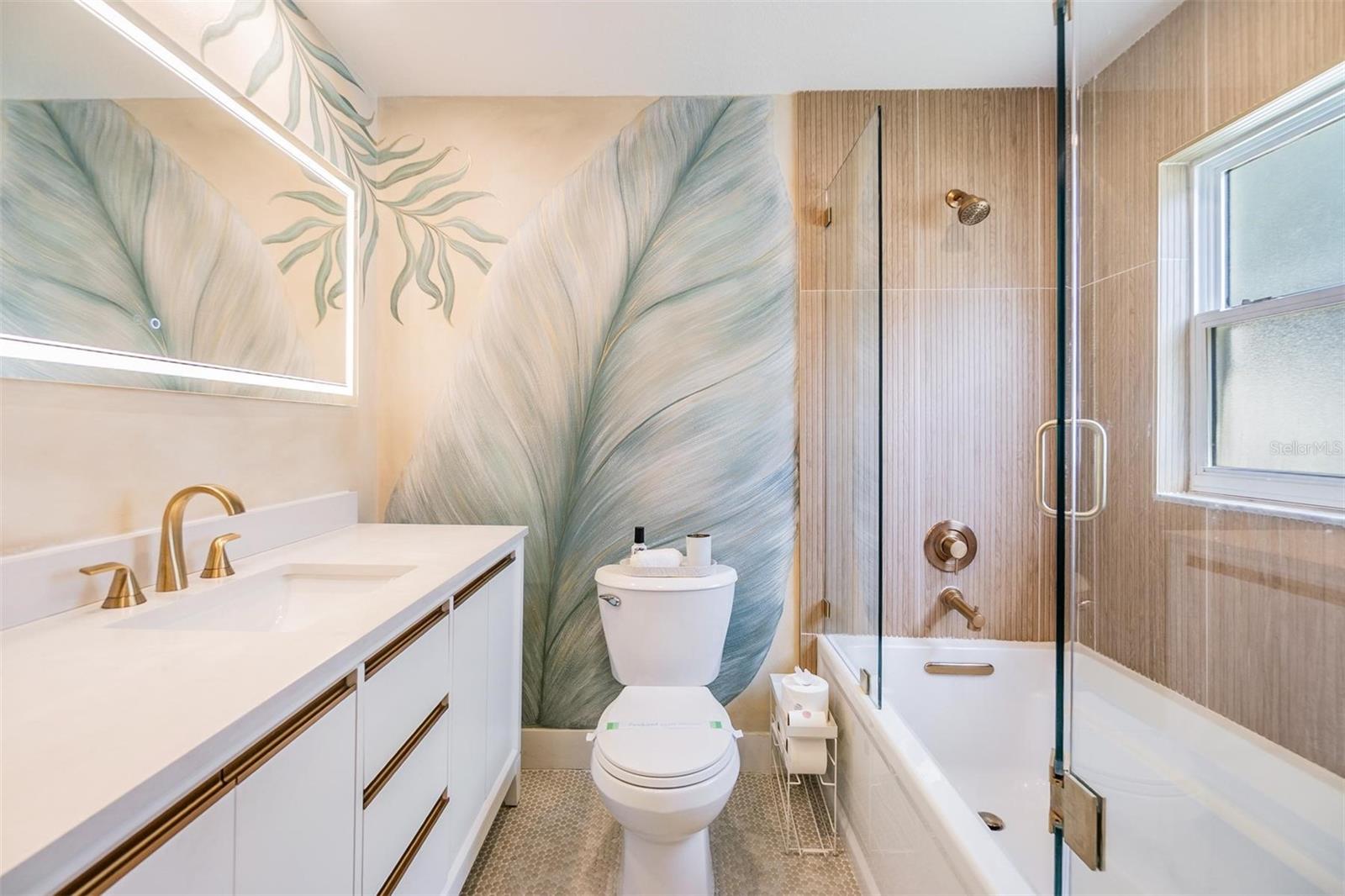 Stylish bathroom featuring a custom-painted accent wall, modern vanity, and gold fixtures for a warm, spa-like feel