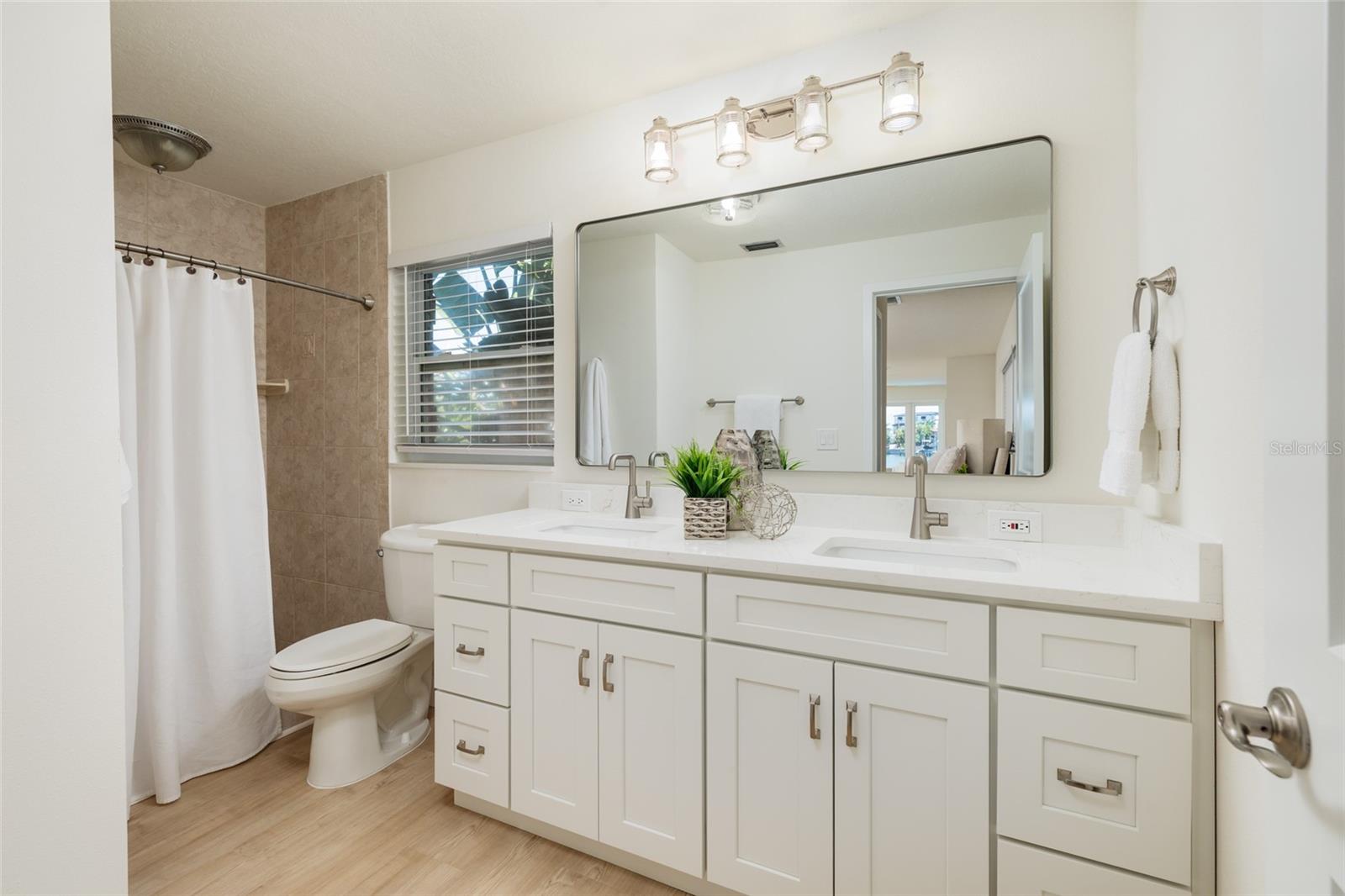 Spa-like primary bathroom features Double vanities and bright coastal finishes