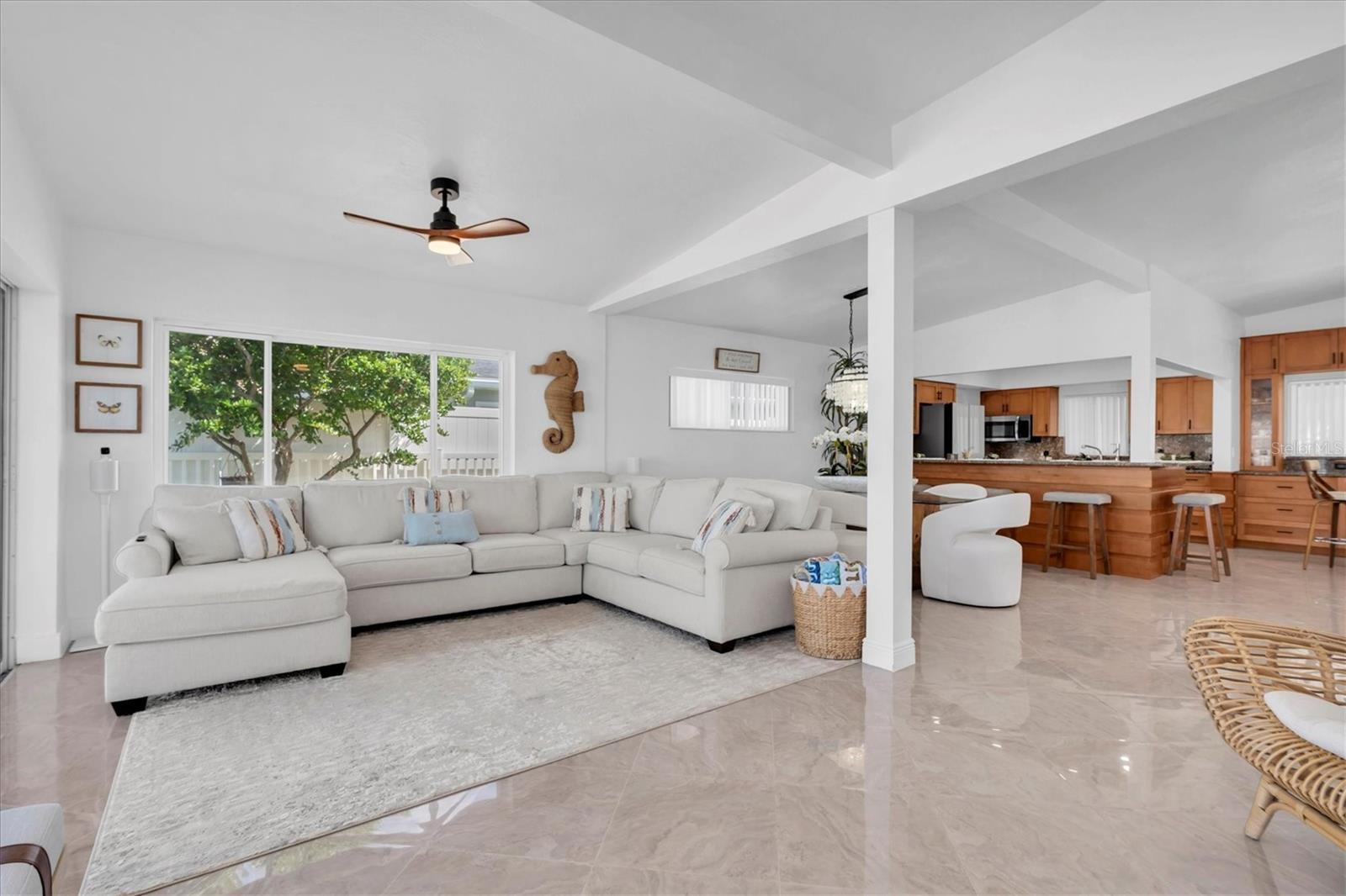 The bright living room with sliding doors, abundant windows, and natural light, offering stunning water views and direct access to a spacious concrete patio