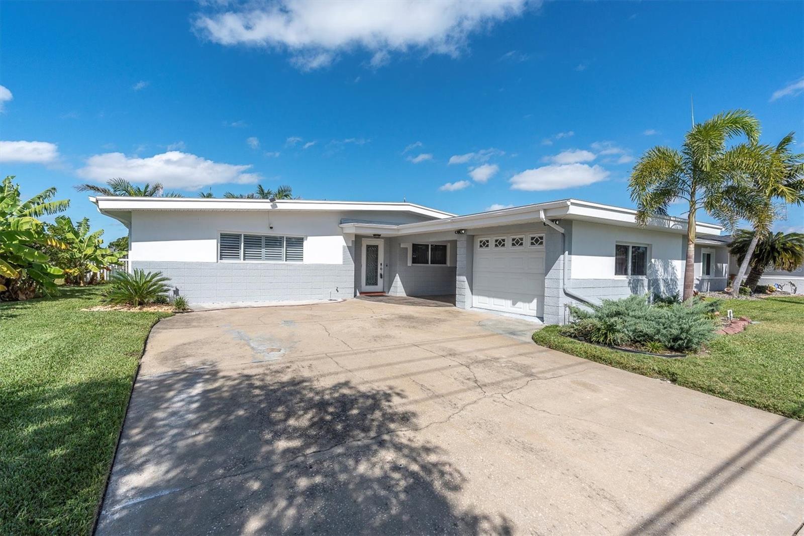 This coastal inspired single-story Floridian home with a large driveway and lush palm landscaping welcomes you to waterfront living!