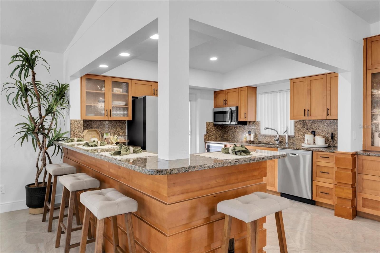 Beautifully appointed kitchen with warm wood cabinetry, granite countertops, and open design showcasing incredible water views.