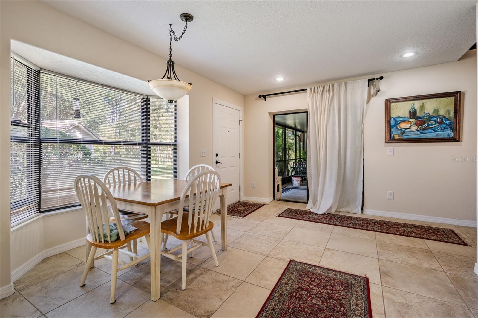 Kitchen table area or can be a dining room, tile flooring, there is a large covered/screened porch through the sliding doors.