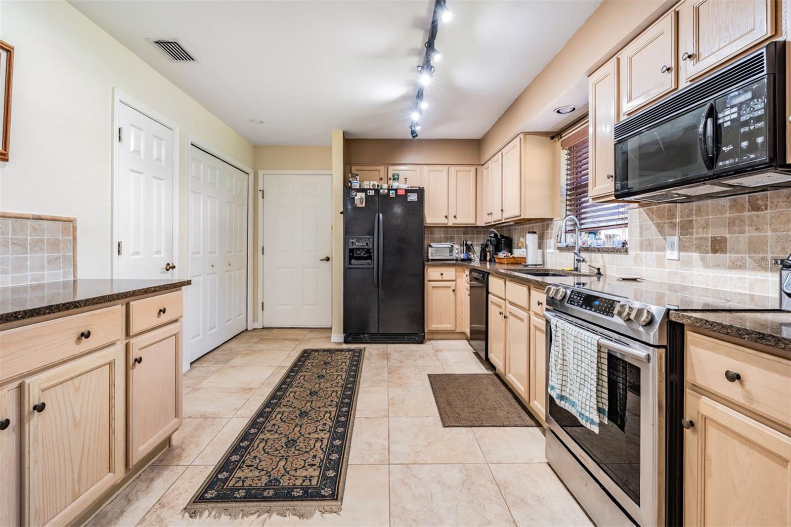 Kitchen with tile flooring, granite counter tops, extra counter space on the left.