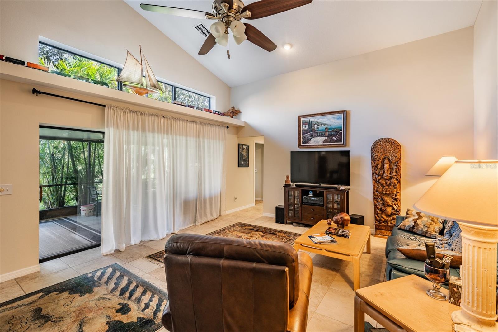 Family Room, Vaulted Ceilings, tile flooring, ceiling fan with light fixture, Large Sliders overlooking the porch area that is screened in, lots of sunlight with the upper windows.