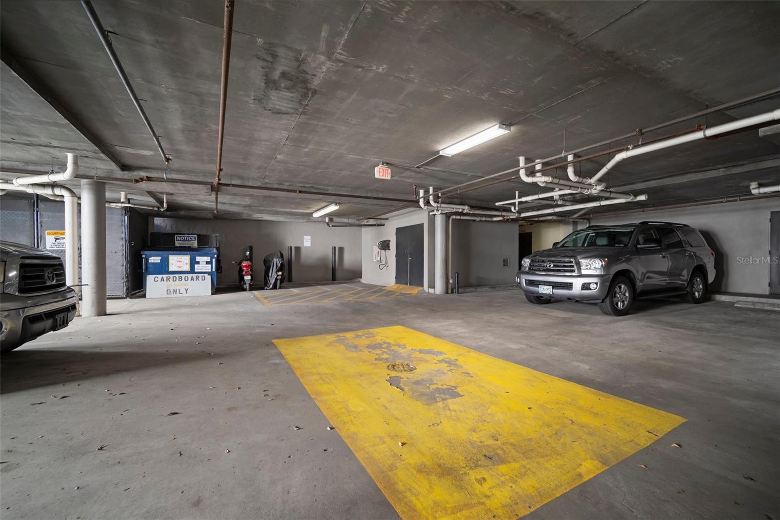 Motorcycle parking, car wash pad, large item disposal cage, and cardboard recycling bin