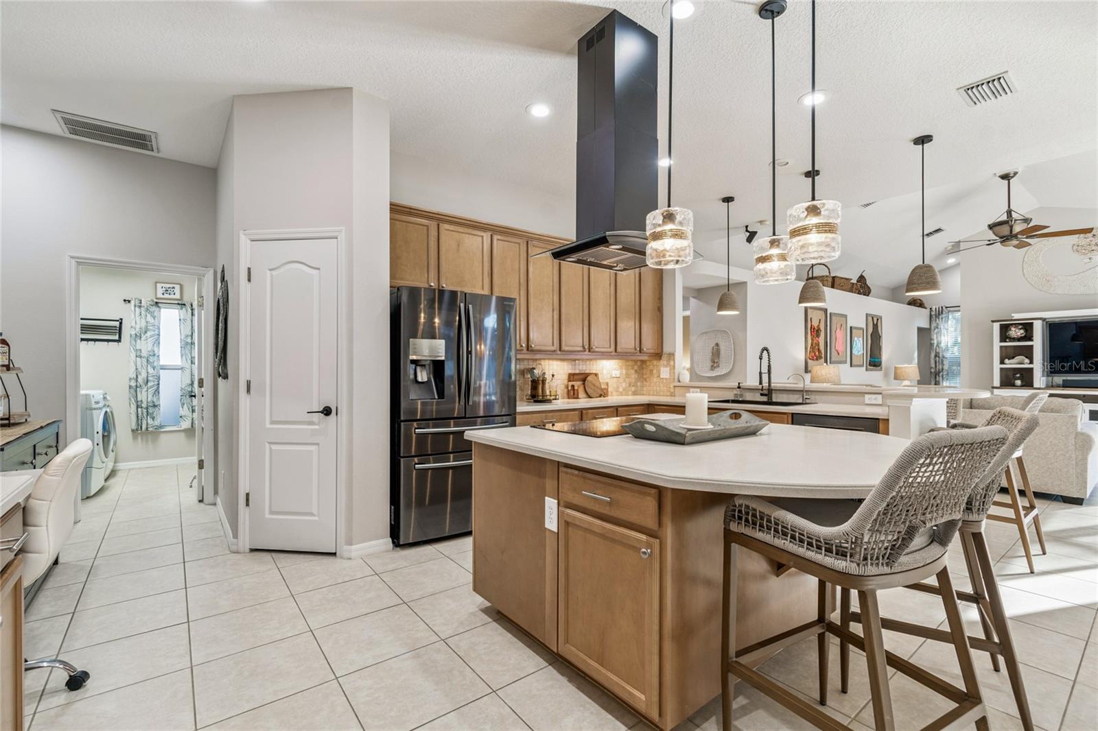 Kitchen view of the center island with built in glass cooktop and vented hood
