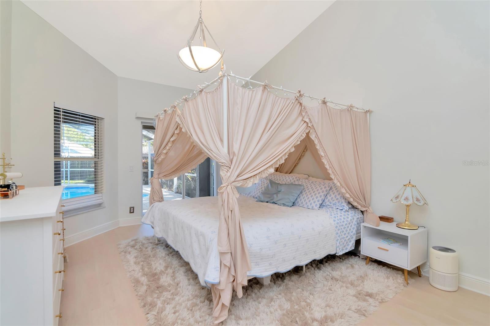 Primary bedroom with lots of natural light and views out to pool