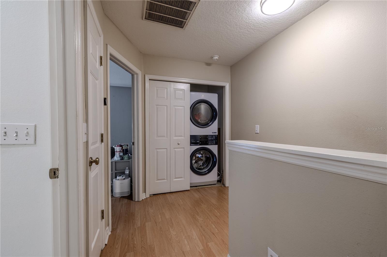 The upper landing integrates form and function with a streamlined laundry closet housing new Electrolux front-load, stacked washer and dryer units. The design emphasizes convenience and clean lines, keeping the home’s flow uninterrupted and efficient.