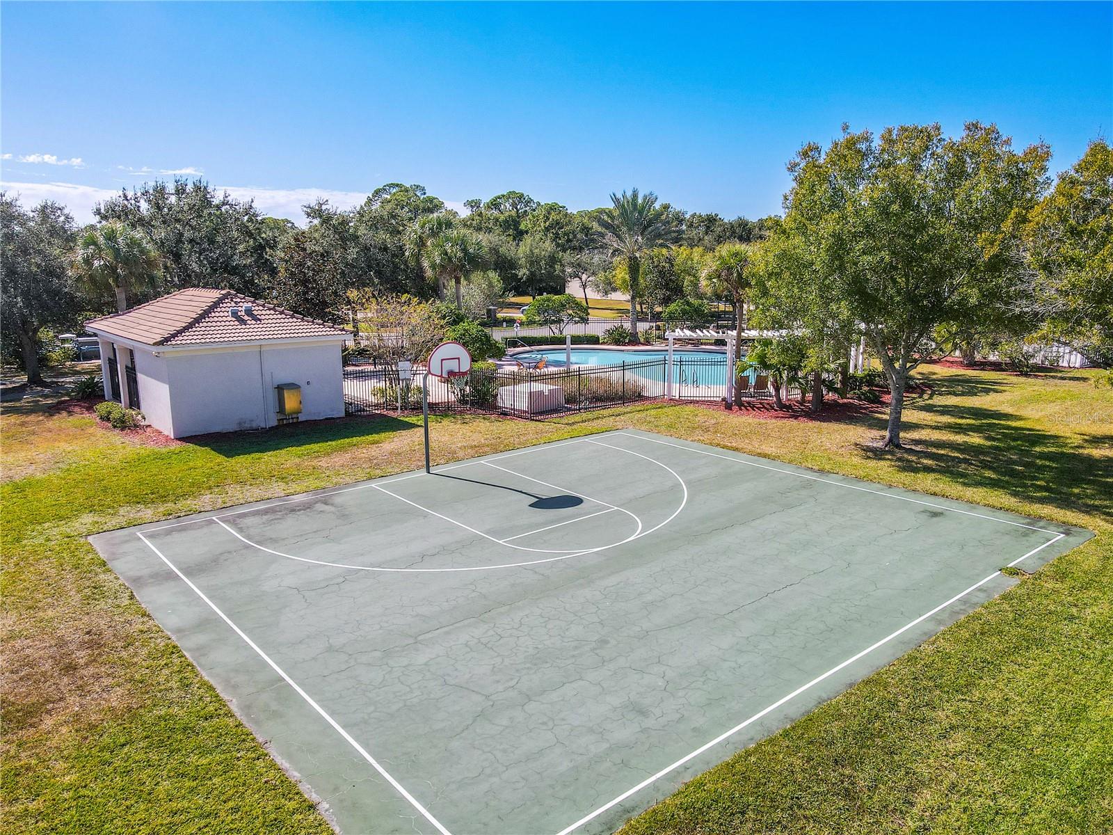 The community amenities combine clean, functional design with natural surroundings. A pool and a sleek basketball court sit amid open green space and trees, offering a balanced setting for recreation, exercise, and relaxation.