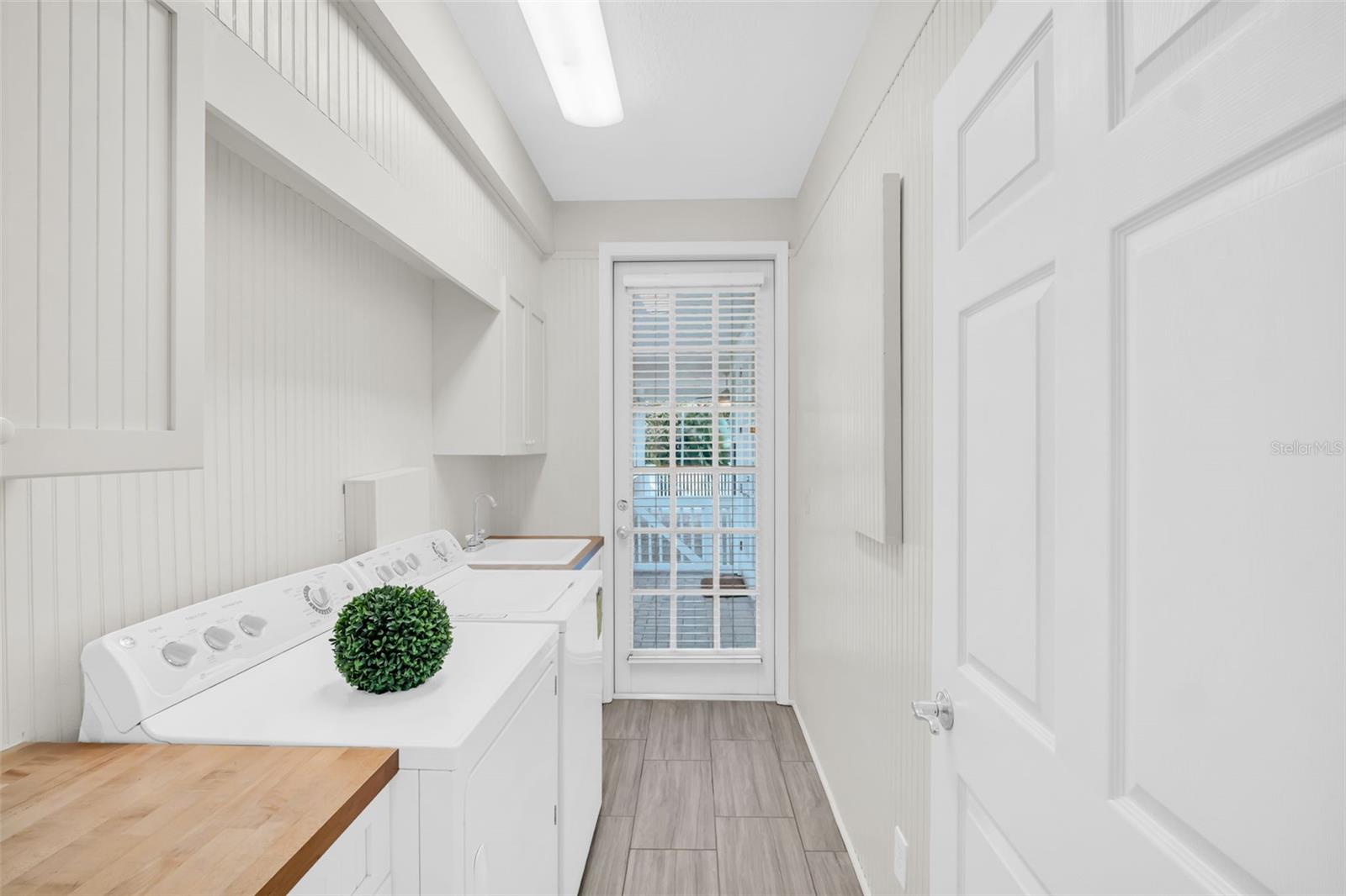Laundry room adjacent from the pantry with butcherblock countertops, deep utility sink, & access to rear patio~