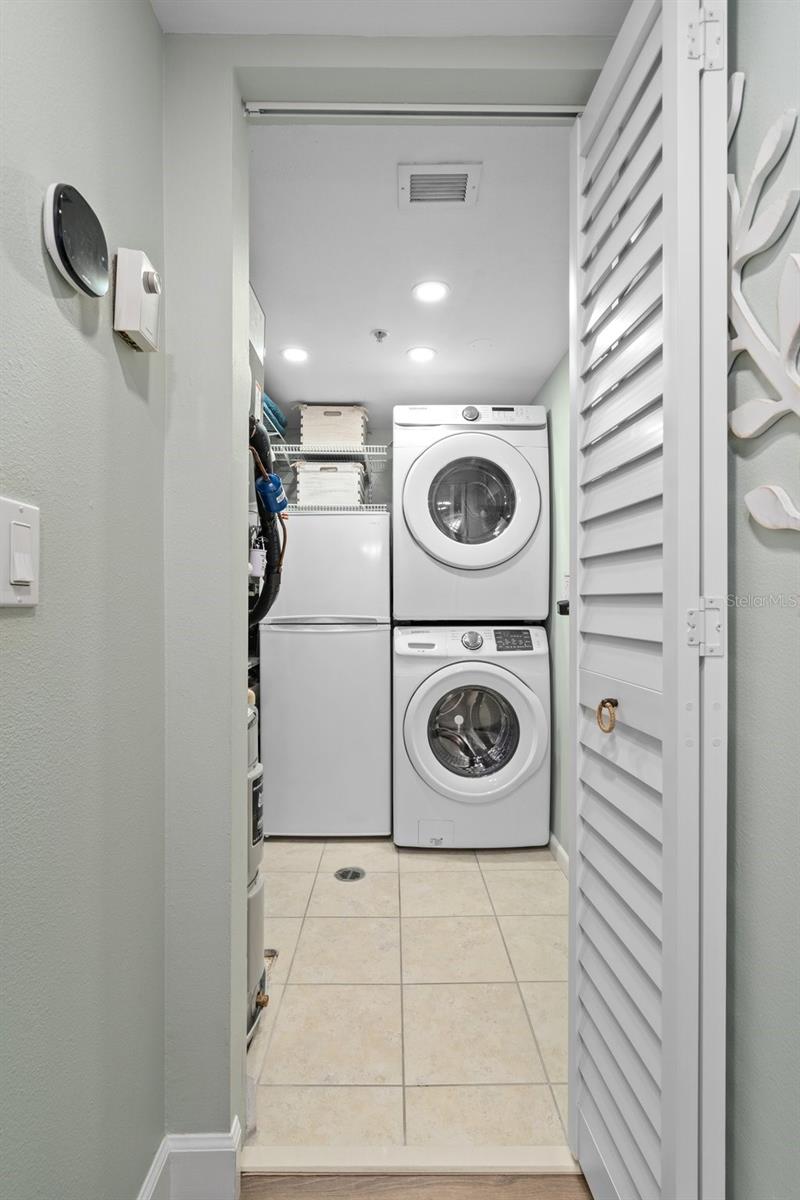 Full laundry room with storage and extra refrigerator.