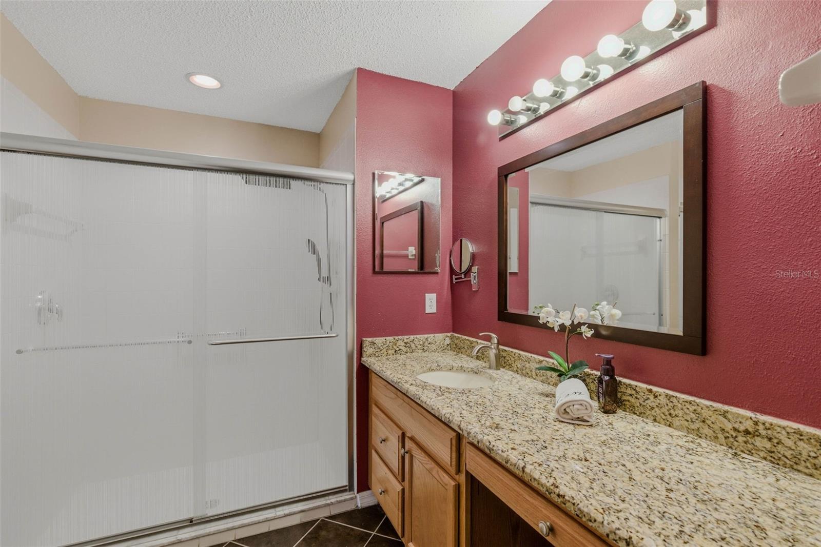 Alternate view emphasizes upgraded finishes—granite cabinets and stylish glass shower doors