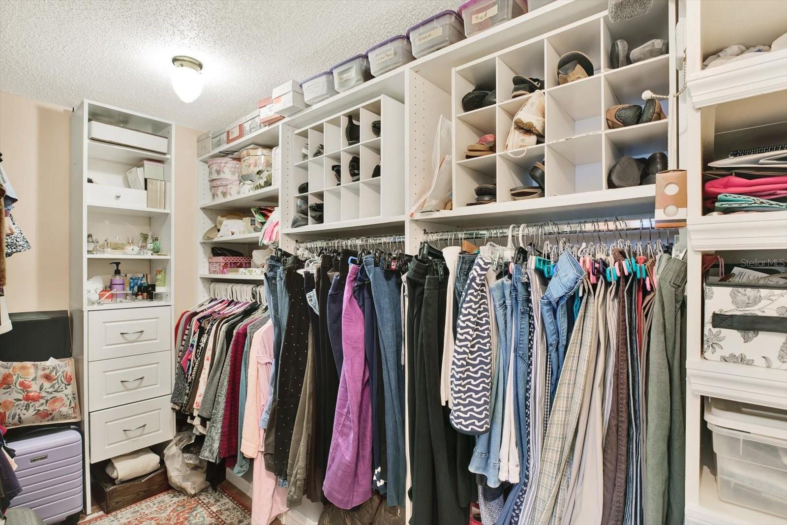 Primary walk-in closet with floor to ceiling built-ins.