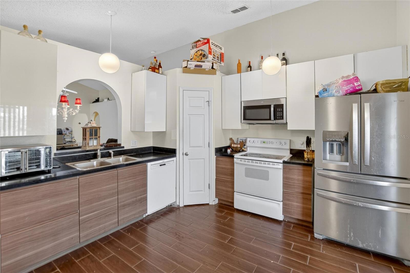 Kitchen.  Pantry door in the center. Arched pass thru to dining area to the left.