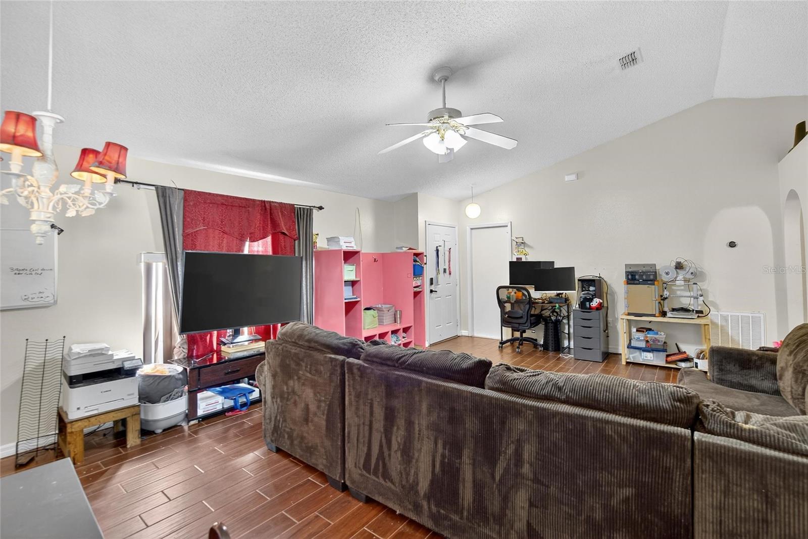 Family room view from dining area.  Entry door to back left.  Garage entry to the right.  Secondary bedroom hallway to far left.