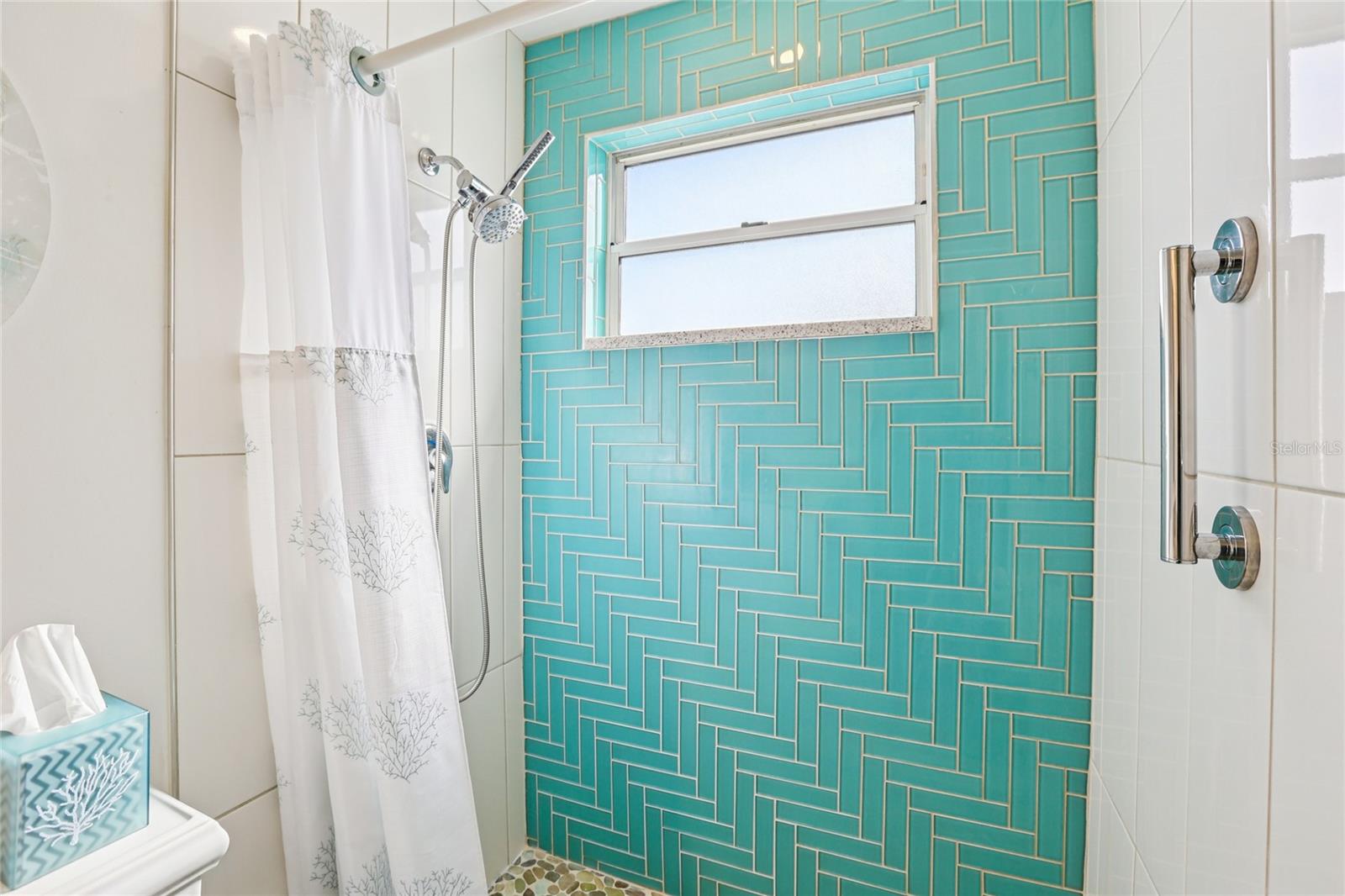 The shower features dual spouts: a handheld and a stationary.