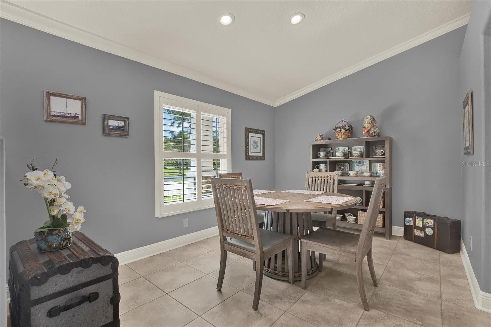 The dining room boasts of dramatic high ceilings with recessed lighting and plantation shutters