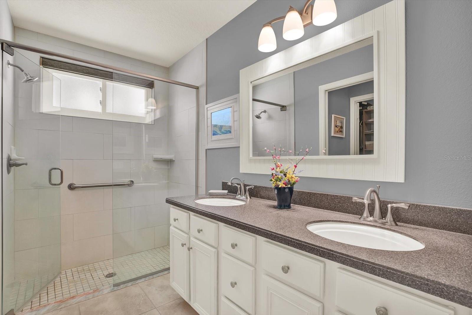 Primary bath has light pouring through the frosted no-peek windows, subway tile in the shower, and a full glass enclosure.