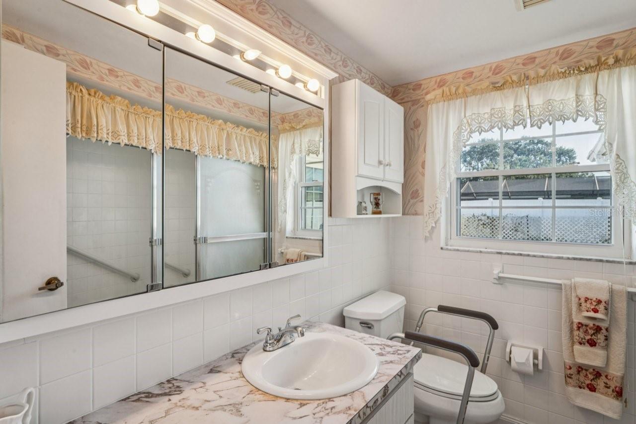 Guest bathroom has single vanity, window and ceramic tile flooring