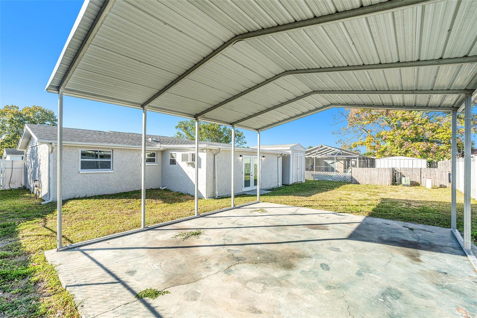 Large fenced in backyard with shed and covered pad