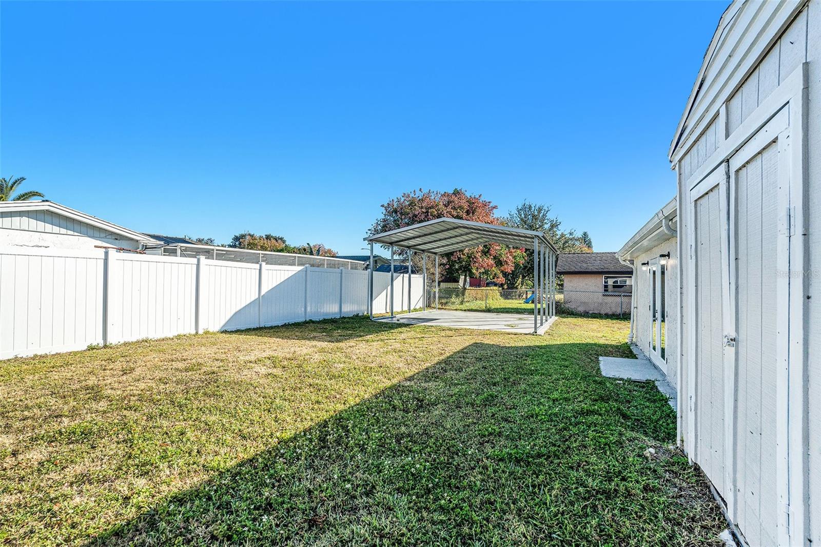 Large fenced in backyard with shed and covered pad