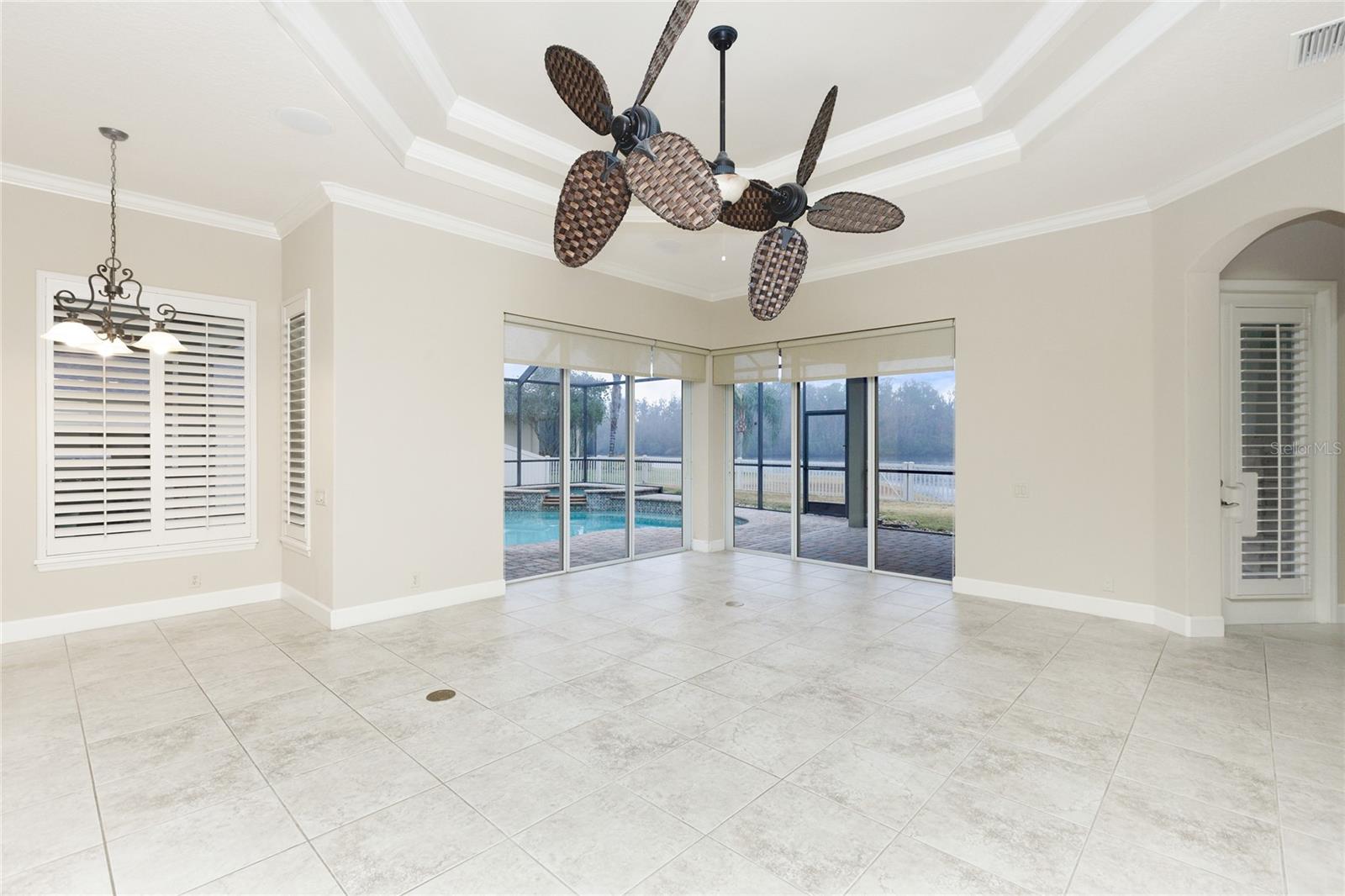Great room with coffered ceilings, crown molding and pocket sliders to pool