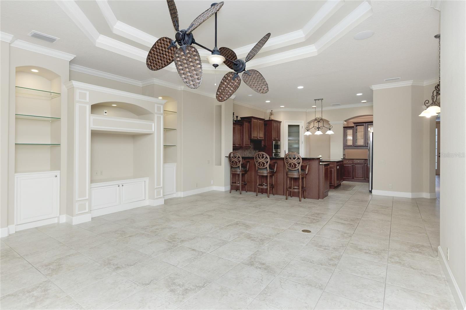 Great room with coffered ceilings, crown molding and view of kitchen