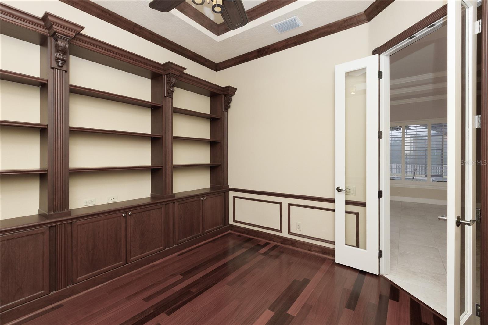 Office with built in bookshelves and wood flooring