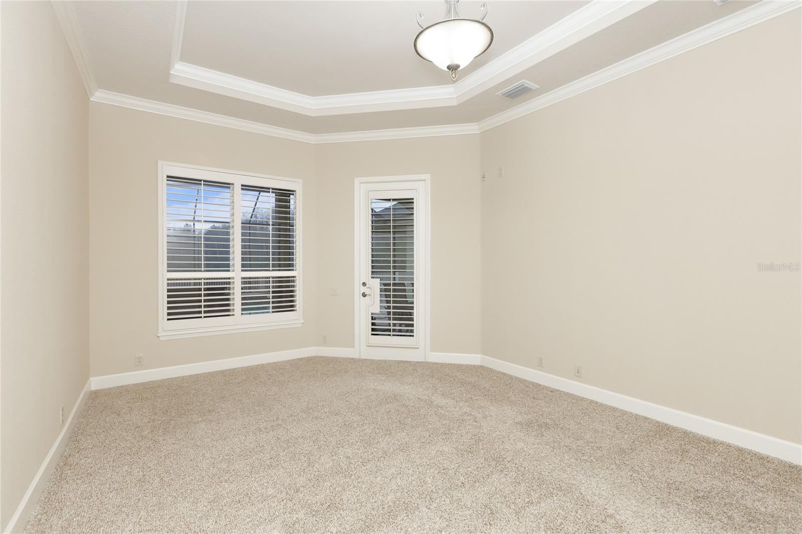 Master Bedroom with plantation shutters, door to pool, coffered ceilings and crown moldling