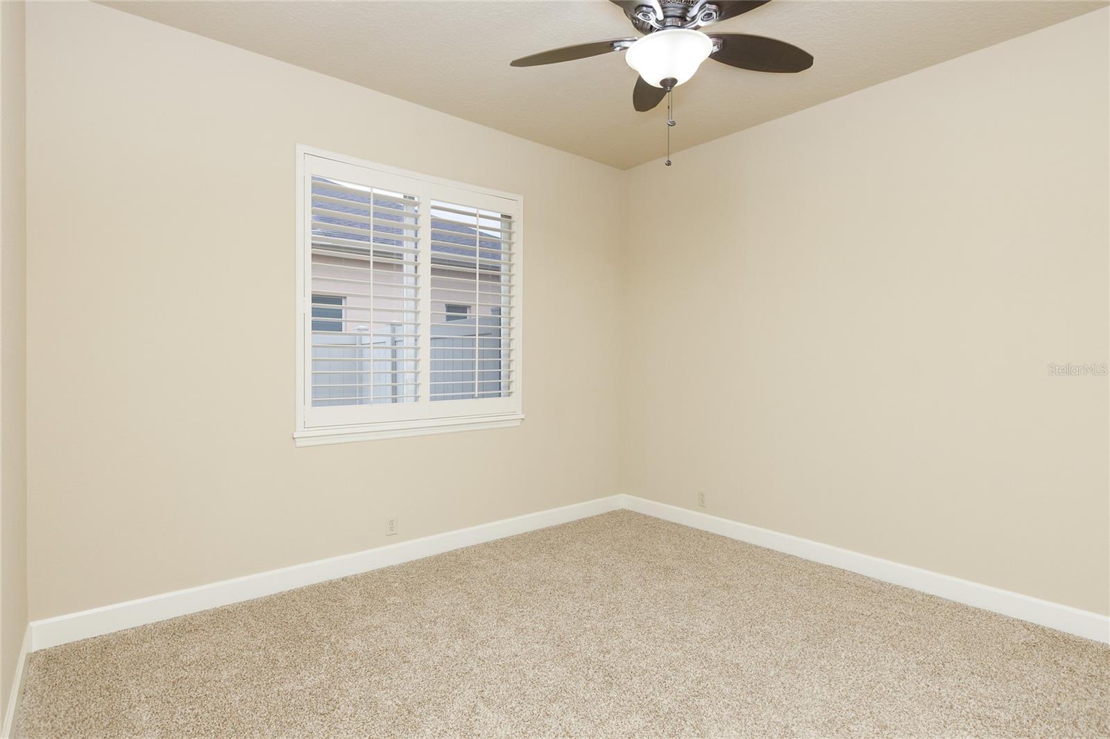 Bedroom 2 with plantation shutters and ceiling fan