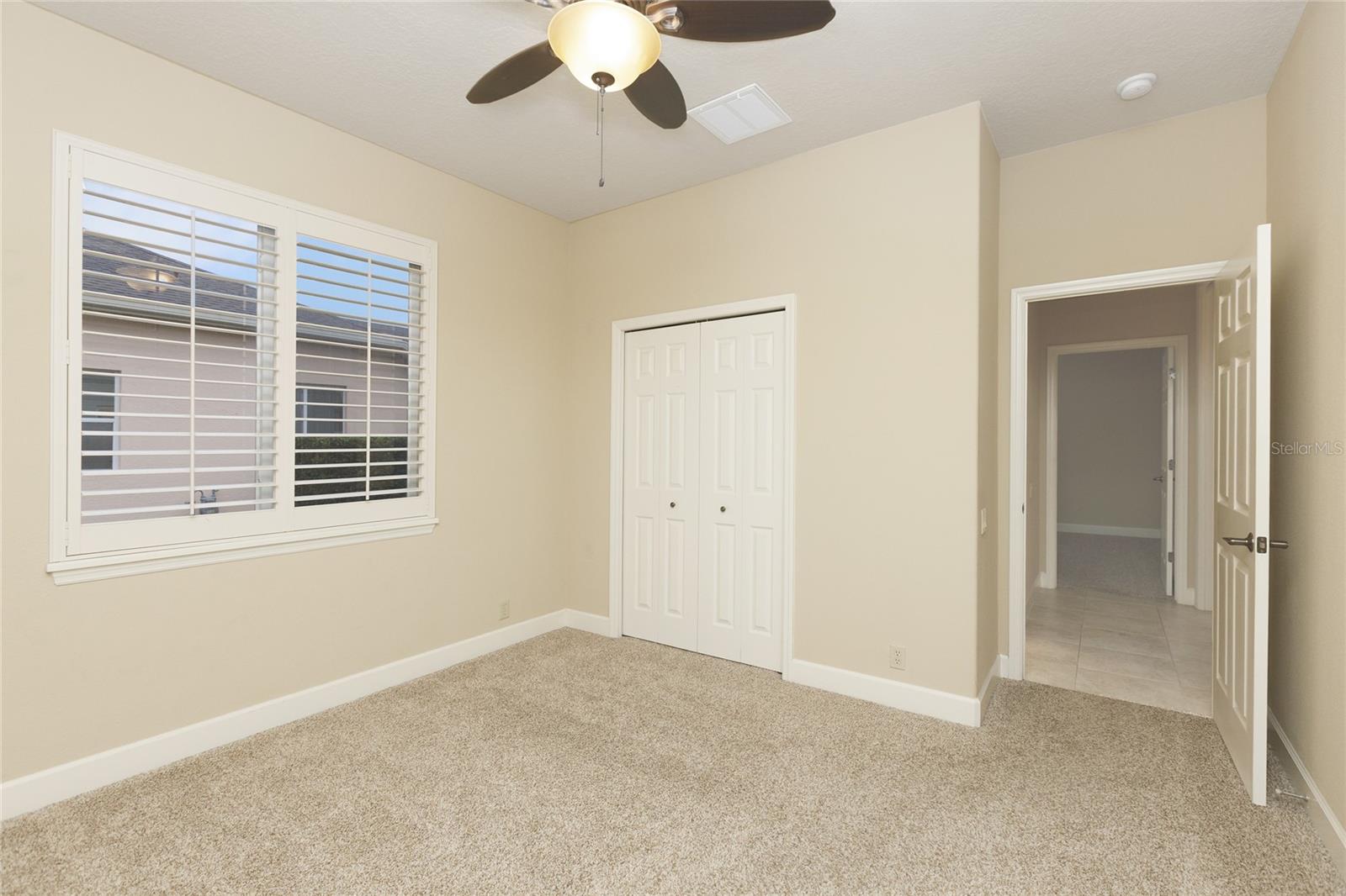 Bedroom 4 with plantation shutters and ceiling fan