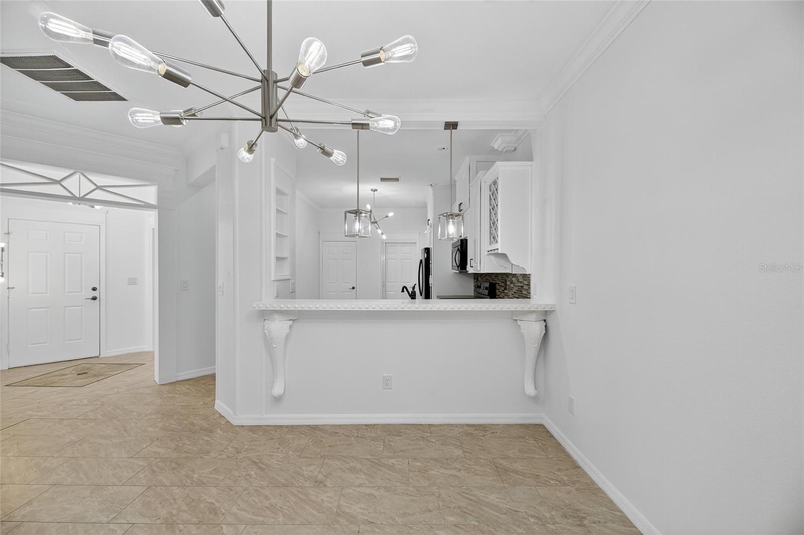 View of the dining room, breakfast bar and front door. Notice the detailing above the doorway!