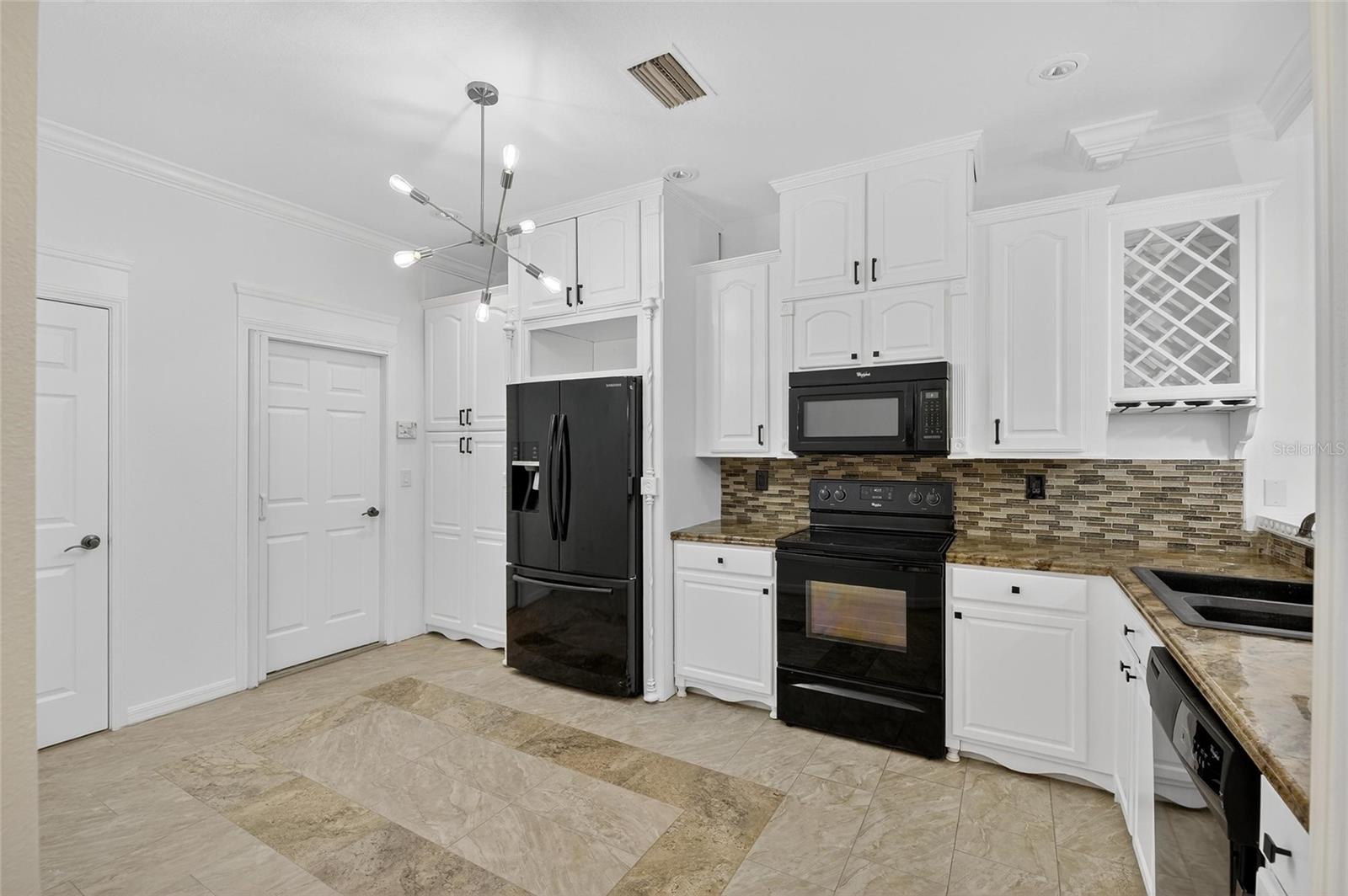 Looking into the beautiful white wood kitchen. The door in the corner leads to the garage.