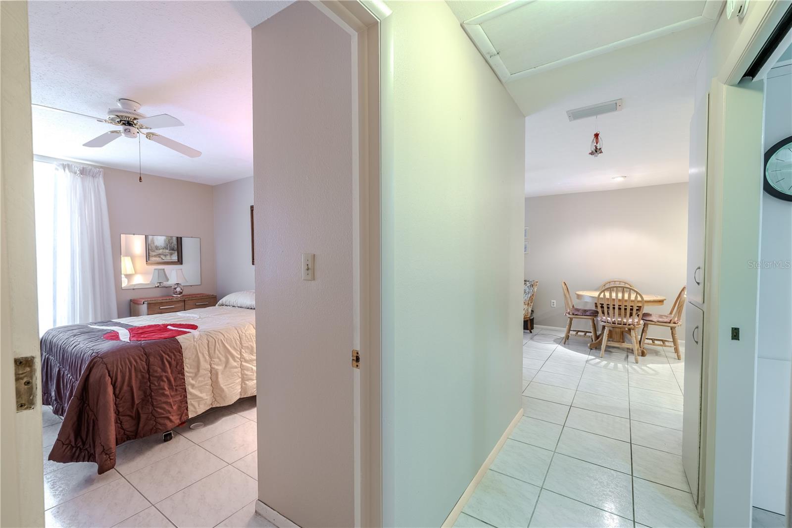 View from the hallway into the second bedroom with a clear sightline to the dining area, showcasing the home’s thoughtfully designed wide hallway for easy wheelchair access. The open, flowing layout ensures comfort and convenience while maintaining a bright, welcoming atmosphere, making everyday living and entertaining effortless for all residents.
