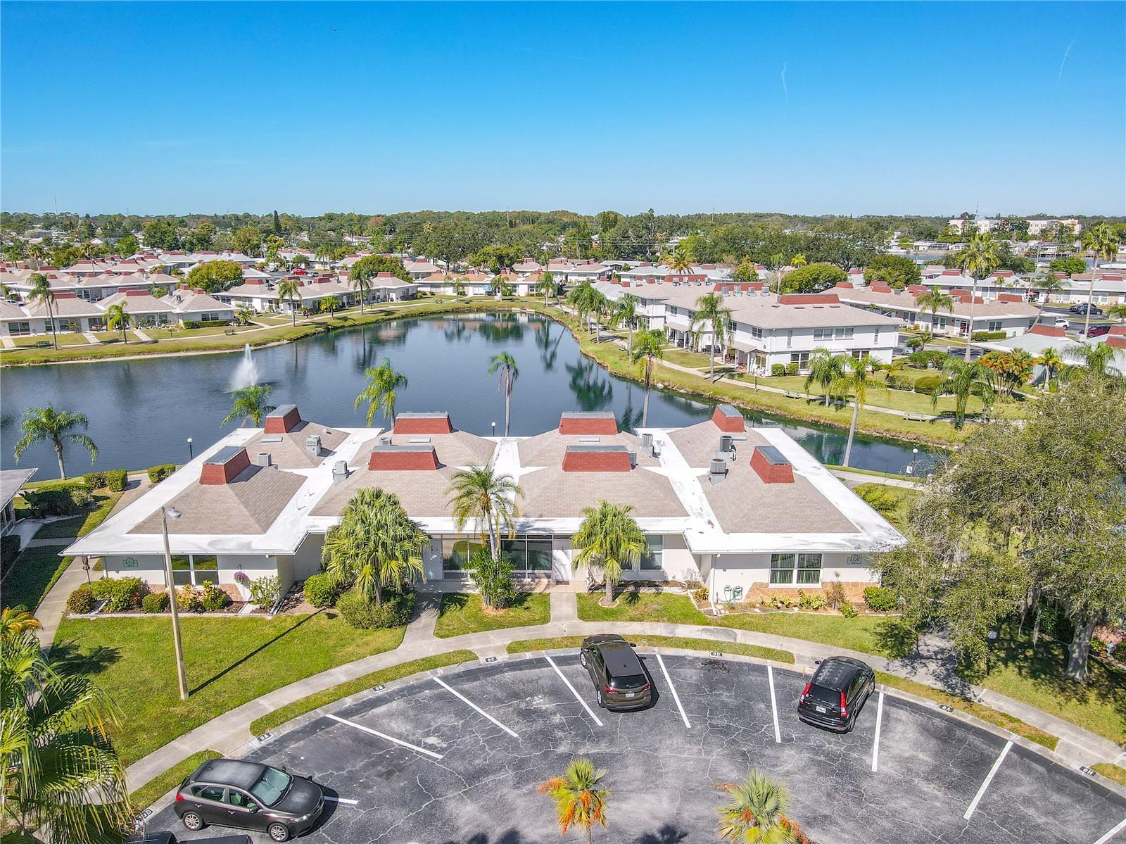 Ground-level view highlighting the spacious cul-de-sac parking area conveniently located in front of the unit. Lush, well-maintained greenery surrounds the area, creating a serene and inviting setting while emphasizing both ease of access and the community’s beautifully landscaped environment.