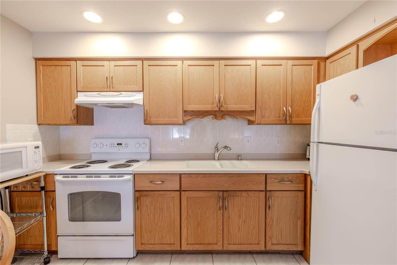 This kitchen’s full complement of appliances provides a functional and stylish backdrop for everyday cooking and entertaining. The combination of warm wood cabinets, durable Corian countertops, dual sinks and appliances creates a welcoming and efficient space