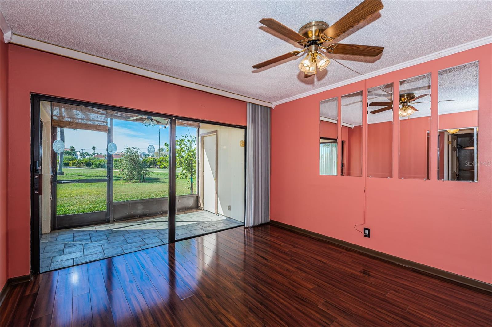 Main living area with laminate flooring and sliding doors leading to private screened patio