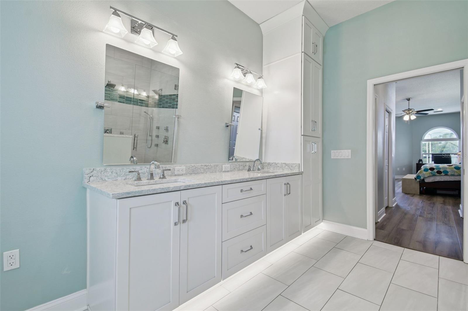 Primary bathroom with dual sinks, quartz countertops, and lots of storage in custom cabinetry