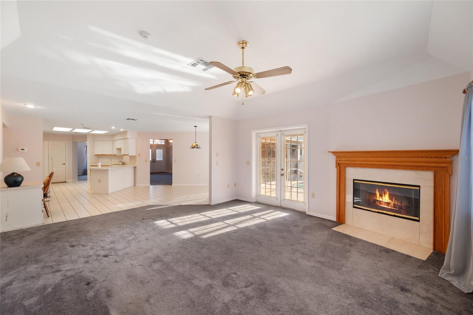 Family room with wood buring fireplace and double door entry to  the pool