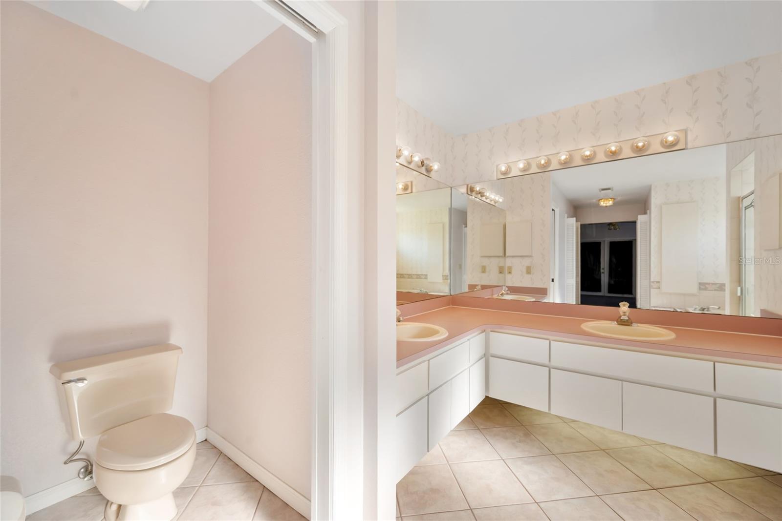 Double sinks separate toilet area.