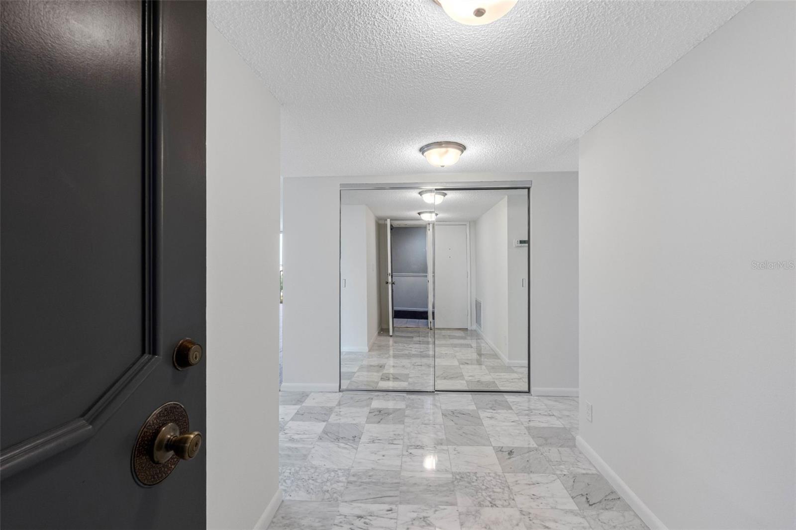 Front Door entry foyer with mirrored closet and marble floors