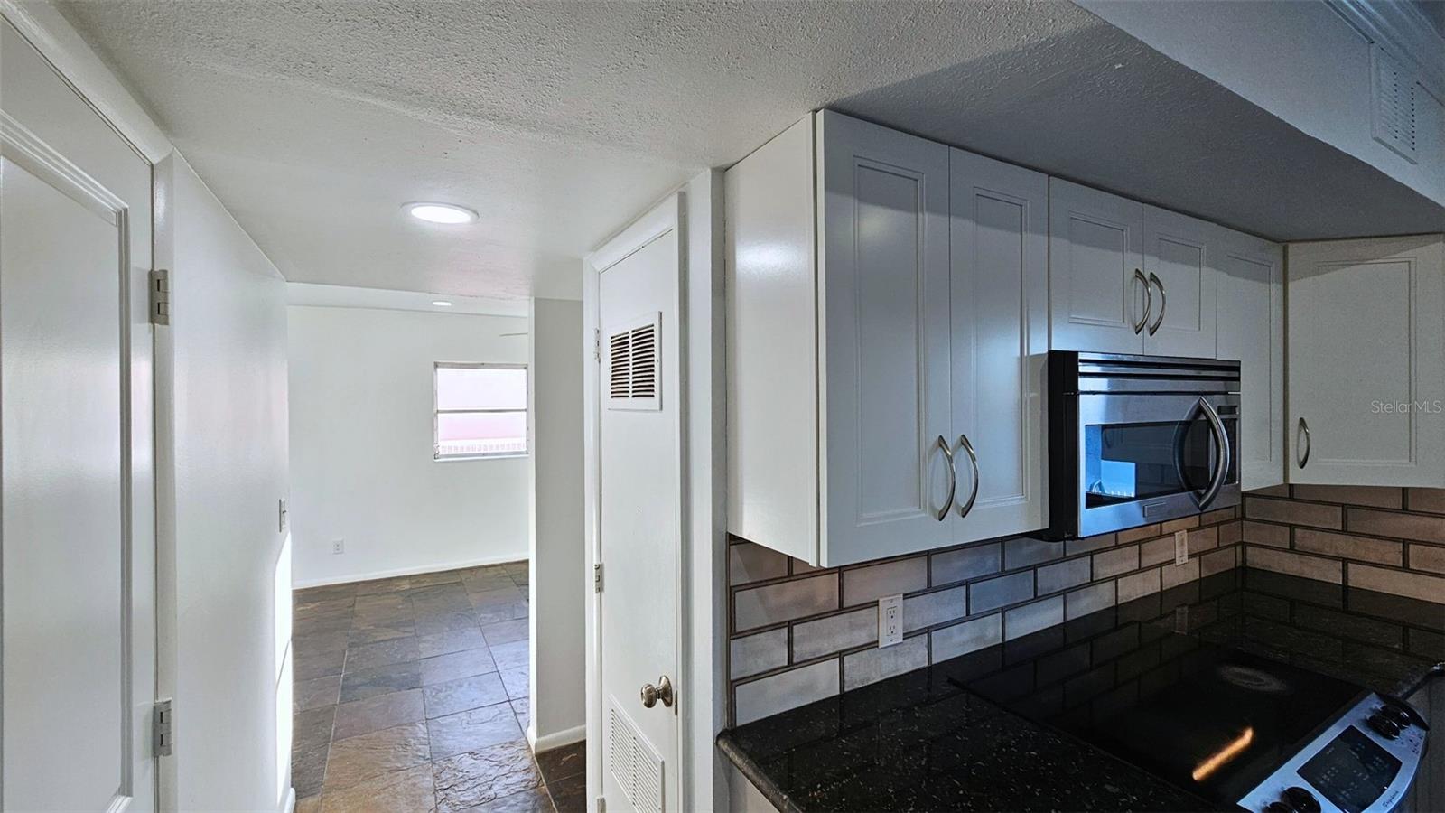 Hallway coming from Half Bath to Kitchen. Flex room in background. cell phone photo.