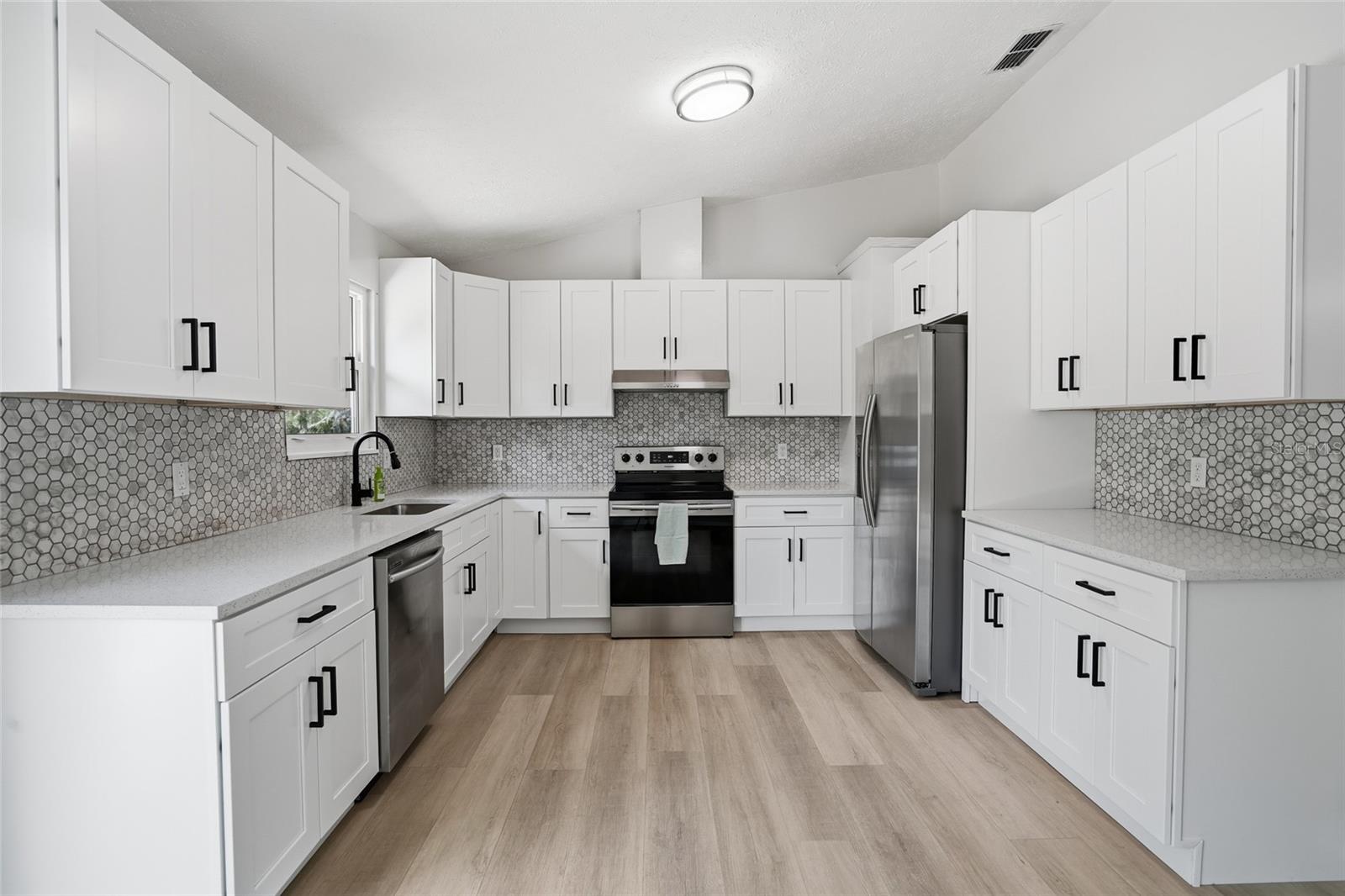 shaker cabinets, subway tile backsplash, stylish pulls, stainless appliances and beautiful quartz counters